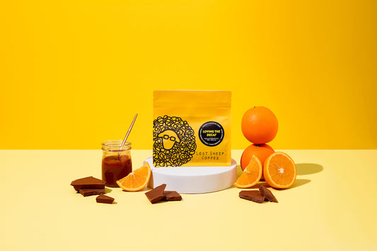 Lost Sheep Coffee's Decaf in yellow packaging surrounded by Milk chocolate, orange and caramel tasting notes