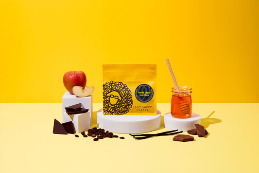 Lost Sheep Coffee's Timor Leste in yellow packaging surrounded by Smooth Apple, and Raisin tasting notes